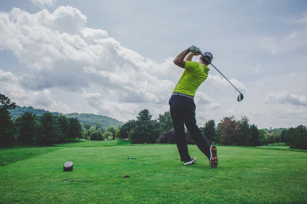 Golfer completing a swing on a tree-lined course
